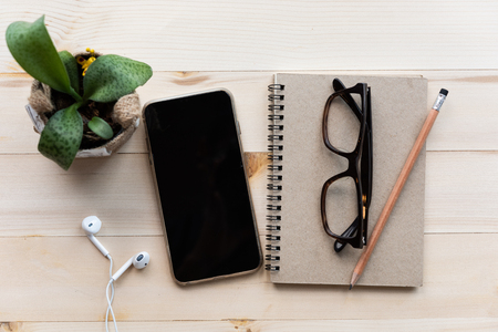 Office desk with notebooks,smartphone,glasses,pencil, on wood table background. Top view with copy space for design. Business and finance conceptの写真素材