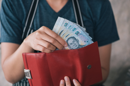 Girl's hands holding Baht bills,money pouchの写真素材
