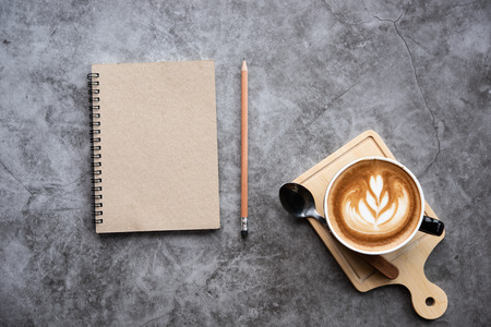Notebook with cup of coffee latte on gray abstract background.の写真素材