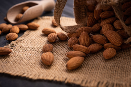Almonds in bag on dark wooden table. Almond concept.の写真素材