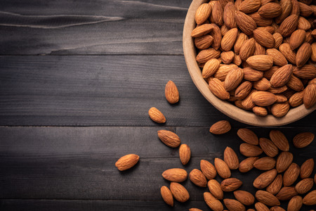 Almonds in wooden bowl on dark wood table. Almond concept with copyspace.topview.の写真素材