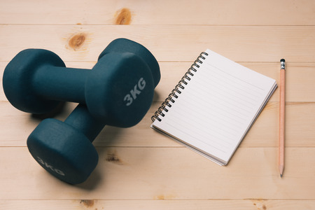 Notebook and fitness tools dumbbell. Weight loss and active lifestyle concept. topview for text and design.の写真素材