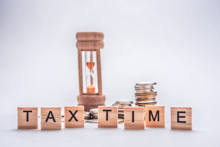 Tax time concept with wooden blocks and coins on white backgroundの写真素材