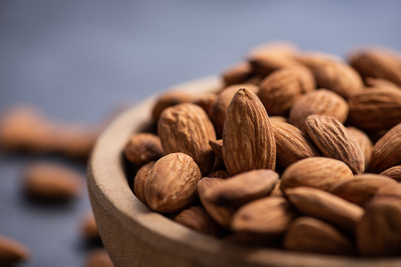 close up of some almonds in wood bowl.almonds concept with coppy space for text or design.の写真素材