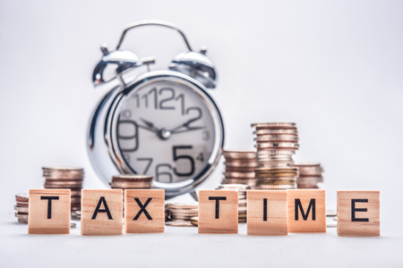 Tax time concept with wooden blocks and coins on white backgroundの写真素材
