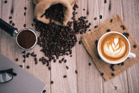 coffee latte art with coffee beans notebook,glasses,pen with copy spaceの写真素材