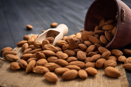 Almonds in bag on dark wooden table. Almond concept.top view.の写真素材