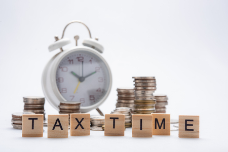 Tax time concept with wooden blocks and coins on white backgroundの写真素材