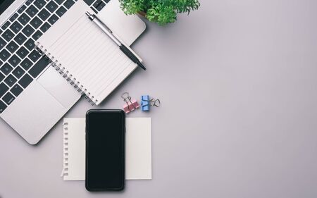 Flat lay, top view office table desk. Workspace with keyboard, office supplies, pencil, green leaf,smartphone on gray background.の写真素材