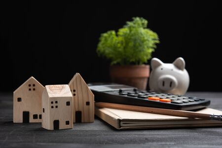 piggybank and Small wooden houses with modern design and calculator for home loans concept.の写真素材