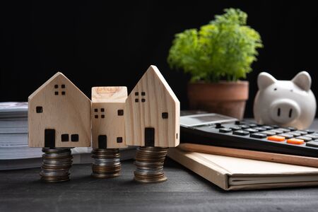 piggybank and Small wooden houses with modern design and calculator for home loans concept.の写真素材