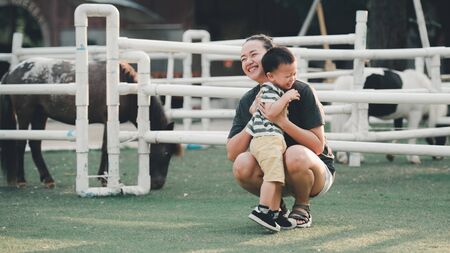 portrait Asian beautiful mothers and children having fun on green field in summer in soft evening lightの写真素材