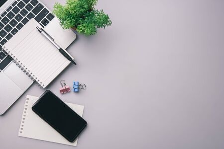 Flat lay, top view office table desk. Workspace with keyboard, office supplies, pencil, green leaf,smartphone on gray background.の写真素材
