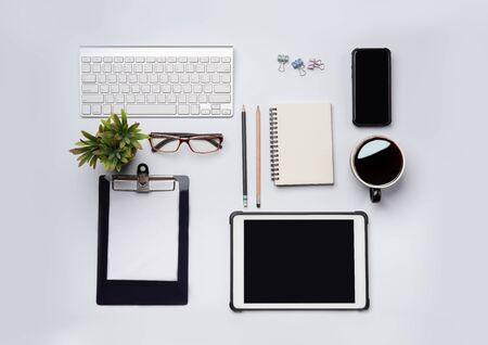 top view of White office desk table with laptop, smartphone and other supplies with cup of coffee. Blank notebook page for input the text in the middle. Top view, flat lay.の写真素材