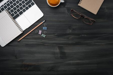 Modern dark wood office desk table with laptop, smartphone and other supplies with cup of coffee. coppy space for input the text in the middle. Top view, flat lay.の写真素材