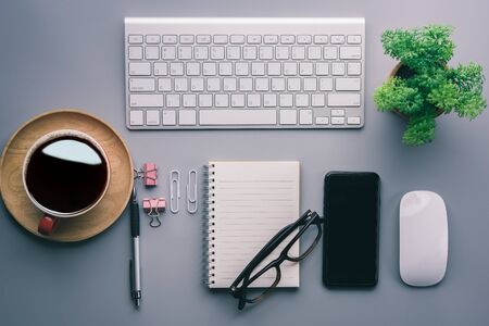 Flat lay, top view office table desk. Workspace with keyboard, office supplies, pencil, green leaf,smartphone on gray background.の写真素材