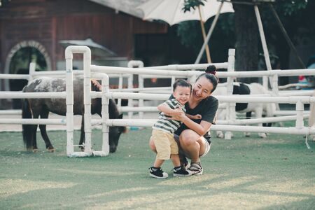 portrait Asian beautiful mothers and children having fun on green field in summer in soft evening lightの写真素材