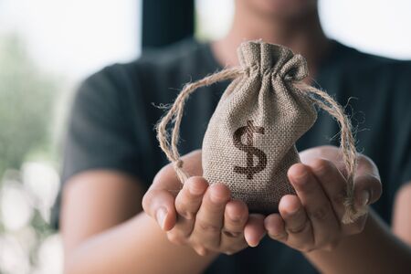 Women hand hold a money bag, a loan or saving money for future investment concept.の写真素材