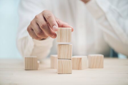 Hand arranging three wood cube stacking. Business concept growth success,hand stack woods block step on table. business development concept.copy space.の写真素材