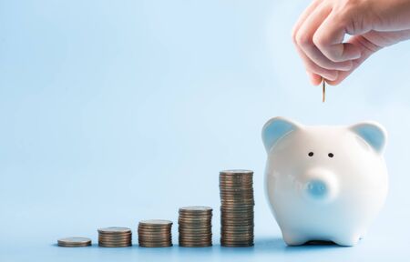 Saving money concept hand putting coin on piggy bankの写真素材