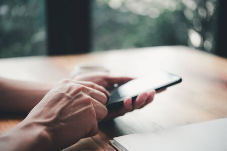 Men's hands are using a smartphone at home.の写真素材