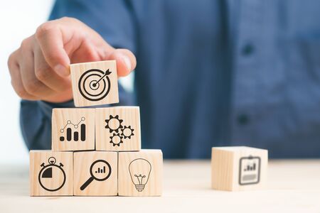 hand of businessman laying wooden blocks with icon business strategy and Action plan, copy space.の写真素材