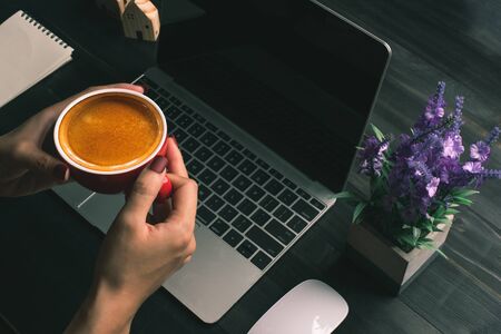 woman working at home or home business, woman holding coffee cup and looking to screen of Notebook computer, home business working concept.の写真素材