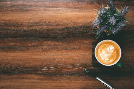 Wood office desk table with cup of coffee, pen and plant pot. Top view with copy space, flat, lay.の写真素材