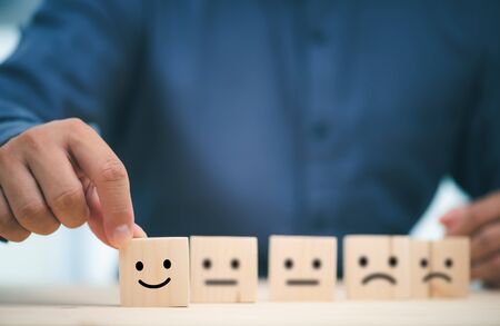 Hand of a businessman chooses a smiley face on wood block cube, The best excellent business services rating customer experience, Satisfaction survey conceptの写真素材