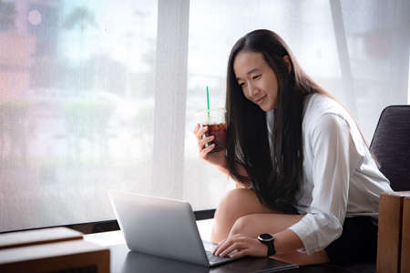Asian girls drinking coffee  at her home.woman use laptop with copy space.の写真素材
