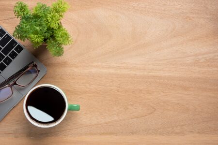 Wooden office desk table with laptop computer, cup of black coffee and supplies. Top view with copy space for text or design, flat lay.の写真素材