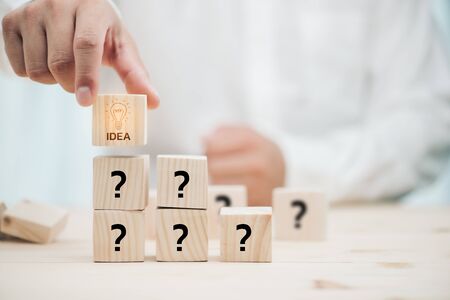 From Many questions to perfect idea. Creative process concept and problem solution.Hand arranging wood cube stacking.の写真素材