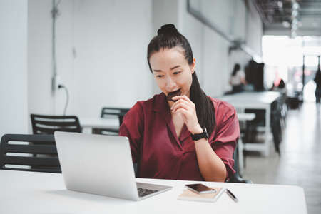 Beautiful Asian girls eating dessert.Take breaks while working at a coffee shop. she using laptop computer.の写真素材