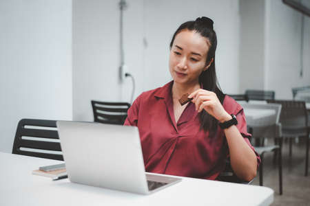 Beautiful Asian girls eating dessert.Take breaks while working at a coffee shop. she using laptop computer.の写真素材