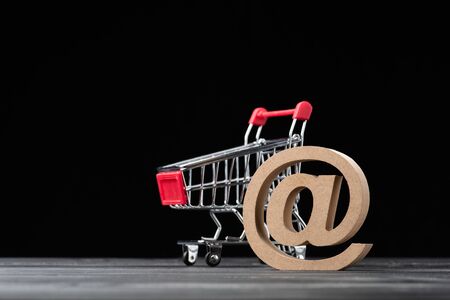model of shopping cart or trolley with @ sing on vintage wood with copyspace,shopping online,online shop concept.の写真素材