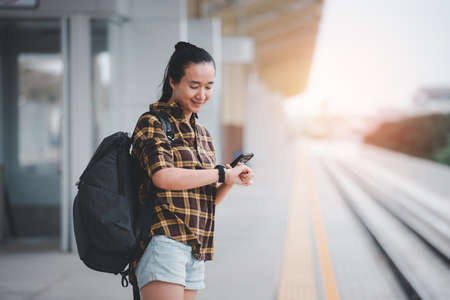 Beautiful asian girl Standing waiting for the train And she is watching a wristwatch. Travel and travel concept.の写真素材