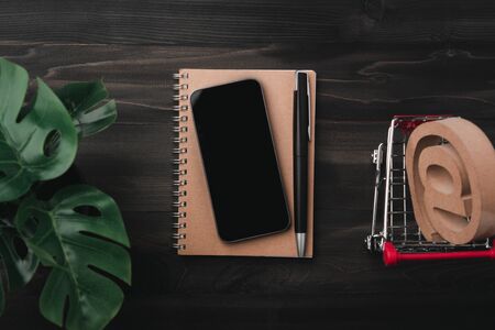 Creative workspace modern dark office desk with smartphone and pen on notebook,mockup topviewの写真素材
