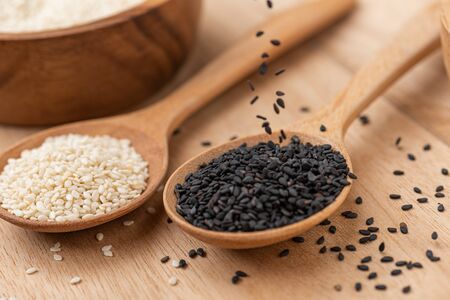 close up of black sesame and white sesame seed on wooden spoon in kitchen.の写真素材