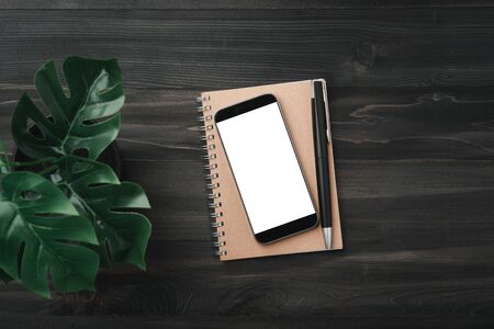 Creative workspace modern dark office desk with blank smartphone and pen on notebook,mockup topviewの写真素材