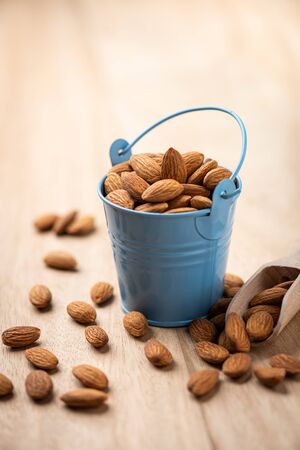 Almonds in blue bucket
 on wooden table. Almond concept with copyspace.の写真素材
