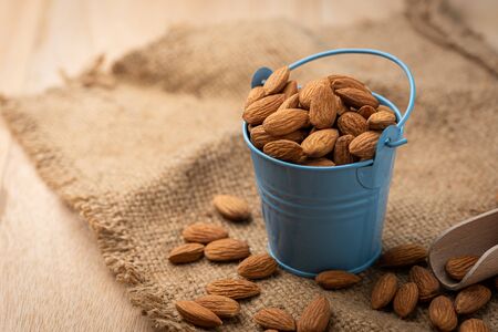 Almonds in blue bucket
 on wooden table. Almond concept with copyspace.の写真素材