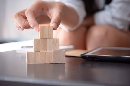 Hand arranging wood cube stacking. Business concept growth success,hand stack woods block step on table. business development concept.copy space.の写真素材