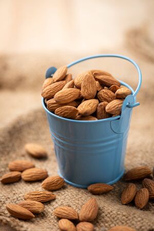 Almonds in blue bucket
 on wooden table. Almond concept with copyspace.の写真素材