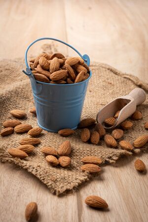 Almonds in blue bucket
 on wooden table. Almond concept with copyspace.の写真素材