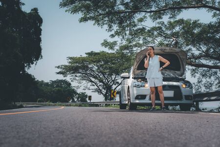 woman opening a car hood to check how the car is broken.Broken car concept with beautiful girlsの写真素材