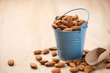 Almonds in blue bucket
 on wooden table. Almond concept with copyspace.の写真素材