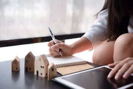 wooden toy house medel with Woman Plan to sign a contract to buy a house, Real estate concept.の写真素材