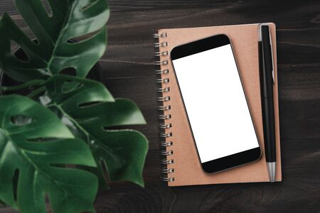Creative workspace modern dark office desk with blank smartphone and pen on notebook,mockup topviewの写真素材