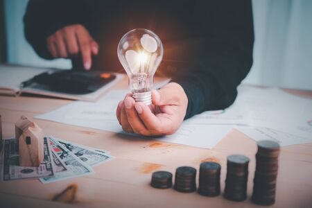 businessman holding lightbulb and use calculator. concept saving money and finance accounting for the future.idea innovation.の写真素材