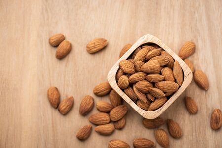 Almonds in wooden bowl on wood table. Almond concept with copyspace.topview.の写真素材